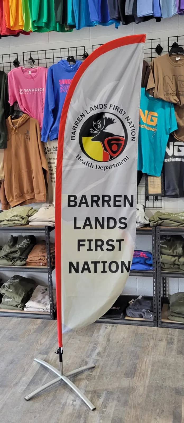 Barren Lands First Nation Health Department feather flag on a cross base, displayed in the Sandstar Graphics shop in Saskatoon