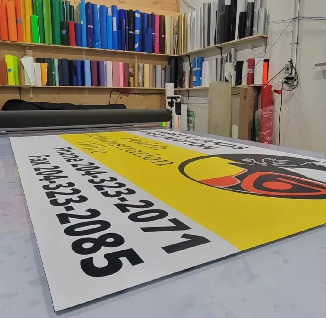 Barren Lands First Nation Health Administration Office sign laid flat on the production table at Sandstar Graphics, with rolls of sign vinyl on the shelves behind